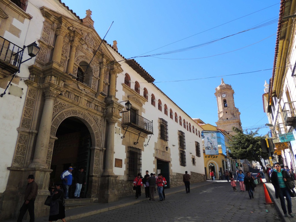 Una calle de Potosí, con la entrada a la Casa de la Moneda en primer término y una de las torres de la Catedral al fondo