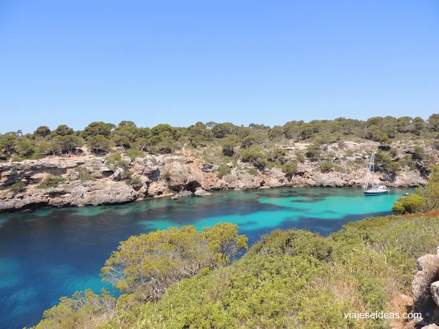 Un barco navegando entre los acantilados de Cala Pi